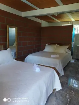 two beds in a room with a brick wall at HOTEL EL POTRILLO in El Peñol