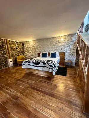 a bedroom with a bed and a stone wall at Eco Hotel Terrabella in Santa Elena
