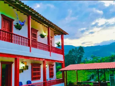 a building with red and white trim and mountains in the background at Casa Hotel Villa Marta in Jericó