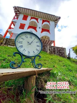a clock sitting on a bench in front of a building at Casa Hotel Villa Marta in Jericó