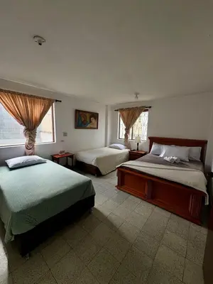 a bedroom with two beds and two windows at Hotel Tahami in Sonsón