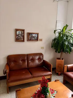 a brown leather couch in a living room with a table at Hotel Tahami in Sonsón