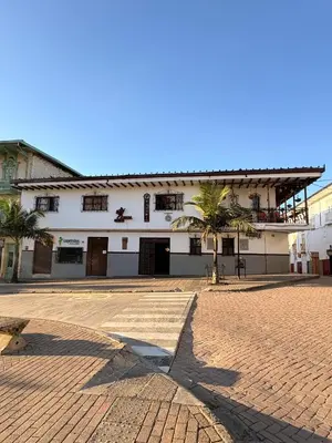 a large white building with a palm tree in front of it at Hotel Tahami in Sonsón
