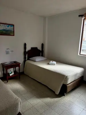 a bedroom with a large bed and a table at Hotel Tahami in Sonsón