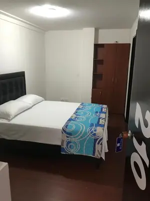 a small bedroom with a bed and a wooden cabinet at Hostal El Eden Manizales in Manizales