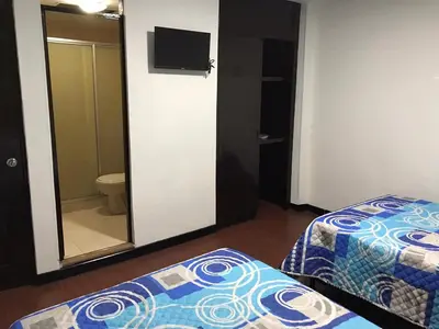 a room with two beds and a bathroom with a mirror at Hostal El Eden Manizales in Manizales