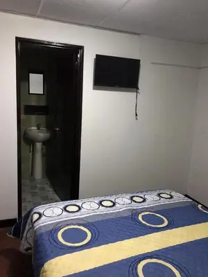 a bedroom with a bed with a blue and yellow blanket at Hostal El Eden Manizales in Manizales