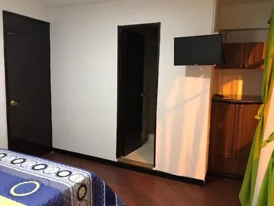 a room with a bed and a mirror and a tv at Hostal El Eden Manizales in Manizales