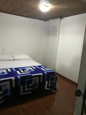 a bedroom with a bed with a blue and white blanket at Hostal El Eden Manizales in Manizales