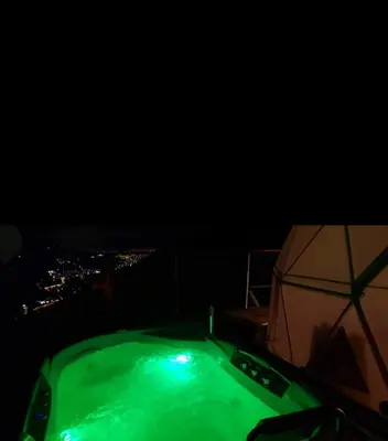 a hot tub at night with a view of a city at Glamping la Fortuna in Girardota