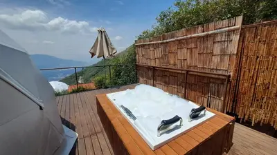 a hot tub on a wooden deck with an umbrella at Glamping la Fortuna in Girardota