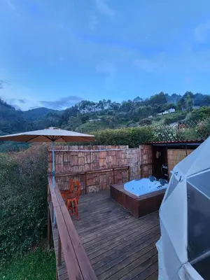 a wooden deck with an umbrella and a hot tub at Glamping la Fortuna in Girardota