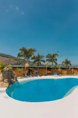 a large swimming pool with palm trees and a building at Hotel Resort Del Cafe in Manizales