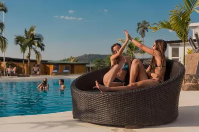 two women sitting in a wicker chair next to a swimming pool at Hotel Resort Del Cafe in Manizales