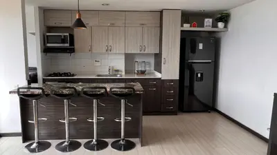 a kitchen with a black refrigerator and bar stools at Paraíso en la ciudad in Medellín