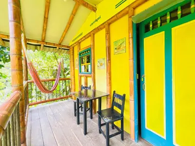 a porch of a house with a table and chairs at Cabañas con cascada privada & vistas a la montaña Naturaleza total in Jardin