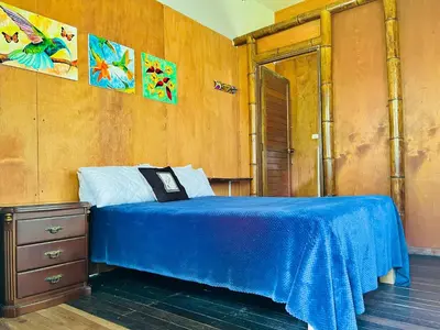 a bedroom with a blue bed and a wooden wall at Cabañas con cascada privada & vistas a la montaña Naturaleza total in Jardin
