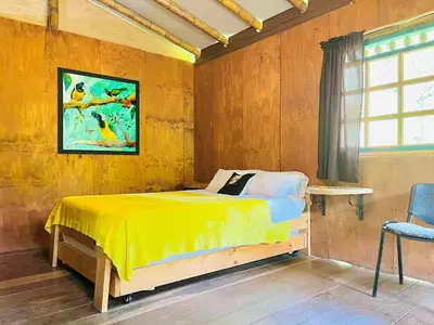 a bedroom with a yellow bed and a window at Cabañas con cascada privada & vistas a la montaña Naturaleza total in Jardin