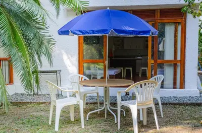 a table and chairs with a blue umbrella at ALDEA VACACIONAL LA FLORIDA Apto 103 Bloque 1 in Santa Fe de Antioquia