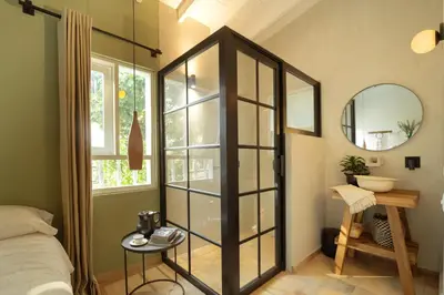 a bedroom with a glass door and a mirror at Hotel Quinta Ladera in Medellín