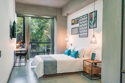 a bedroom with a bed and a large window at Loft 32 Medellín Living in Medellín