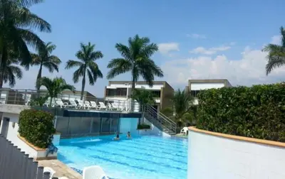 a swimming pool with palm trees in a resort at cabaña en san jeromino in San Jerónimo