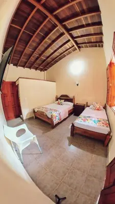 a room with two beds and a chair in it at La Casa de las Flores Hostal in Jardin