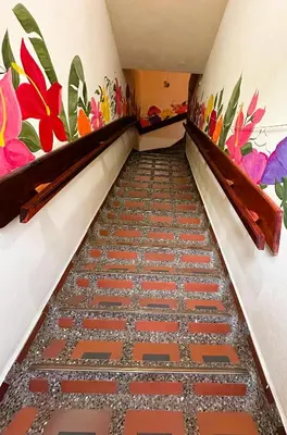 a hallway with a tile floor and flowers on the walls at La Casa de las Flores Hostal in Jardin