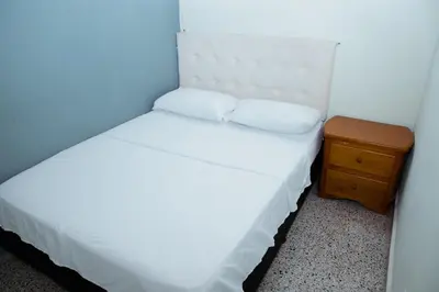 a small bedroom with a white bed and a wooden nightstand at Hotel Casa Verde Guatapé in Guatapé