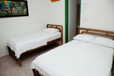 a room with two beds with white sheets at Hotel Casa Verde Guatapé in Guatapé