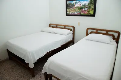 two beds in a room with a picture on the wall at Hotel Casa Verde Guatapé in Guatapé