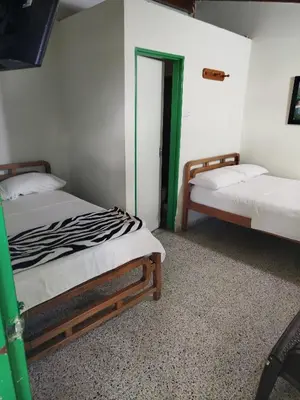 two beds in a room with green and white walls at Hotel Casa Verde Guatapé in Guatapé