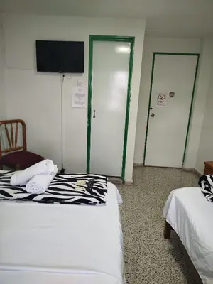 a room with two beds and a tv and two doors at Hotel Casa Verde Guatapé in Guatapé