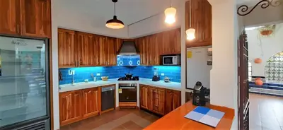 a kitchen with wooden cabinets and a blue tiled wall at Villa del Prado in Medellín