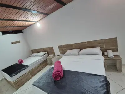 a bedroom with two beds and a table with pink sheets at Hotel Brisas MEDELLIN in Medellín
