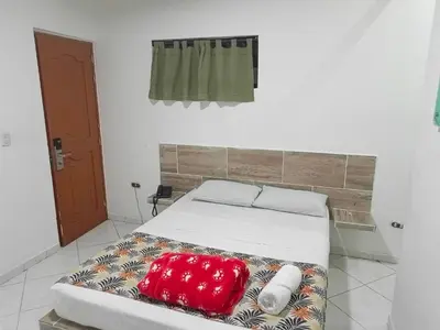 a bed in a room with a red pillow on it at Hotel Brisas MEDELLIN in Medellín