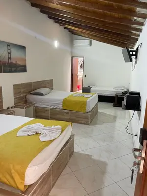 a room with two beds and a television in it at Hotel Brisas MEDELLIN in Medellín