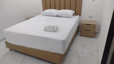 a bed with white sheets and white pillows on it at Hotel Brisas MEDELLIN in Medellín