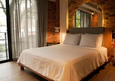 a bedroom with a white bed with a large window at Nomada Hotel Origen in Medellín