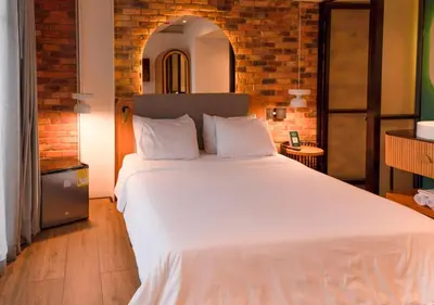 a bedroom with a large white bed with a brick wall at Nomada Hotel Origen in Medellín