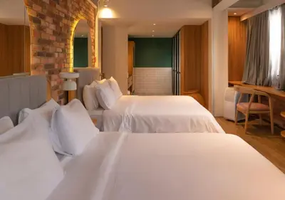 a hotel room with two beds with white sheets at Nomada Hotel Origen in Medellín