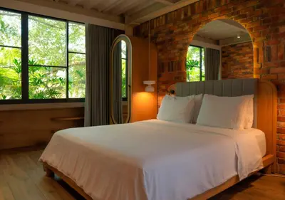 a bedroom with a large white bed with windows at Nomada Hotel Origen in Medellín