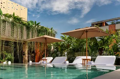 a swimming pool with chairs and umbrellas at Elcielo Hotel Luxury Medellin in Medellín