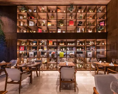 a restaurant with tables and shelves of wine glasses at Elcielo Hotel Luxury Medellin in Medellín