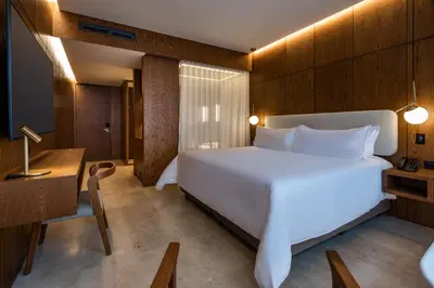 a bedroom with a large white bed and a desk at Elcielo Hotel Luxury Medellin in Medellín