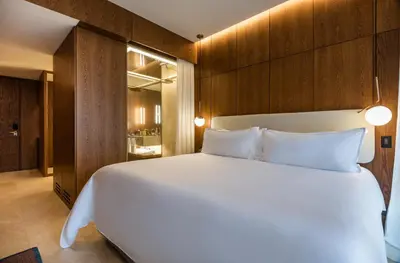 a bedroom with a large white bed with wooden walls at Elcielo Hotel Luxury Medellin in Medellín
