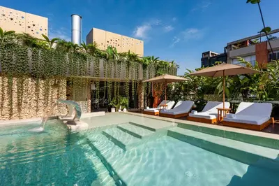 a swimming pool with chairs and umbrellas next to a building at Elcielo Hotel Luxury Medellin in Medellín