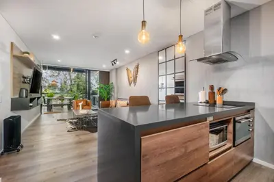 a kitchen with a black counter top and a living room at Olive Living Suites by HOUSY in Envigado
