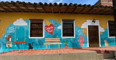a mural on the side of a building with a bench at Casa Amarilla, San Carlos, Antioquia in San Carlos