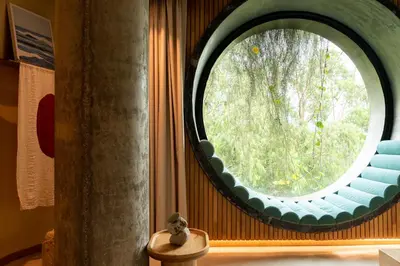 a round window in a room with a blue couch at 23 Hotel Medellin in Medellín